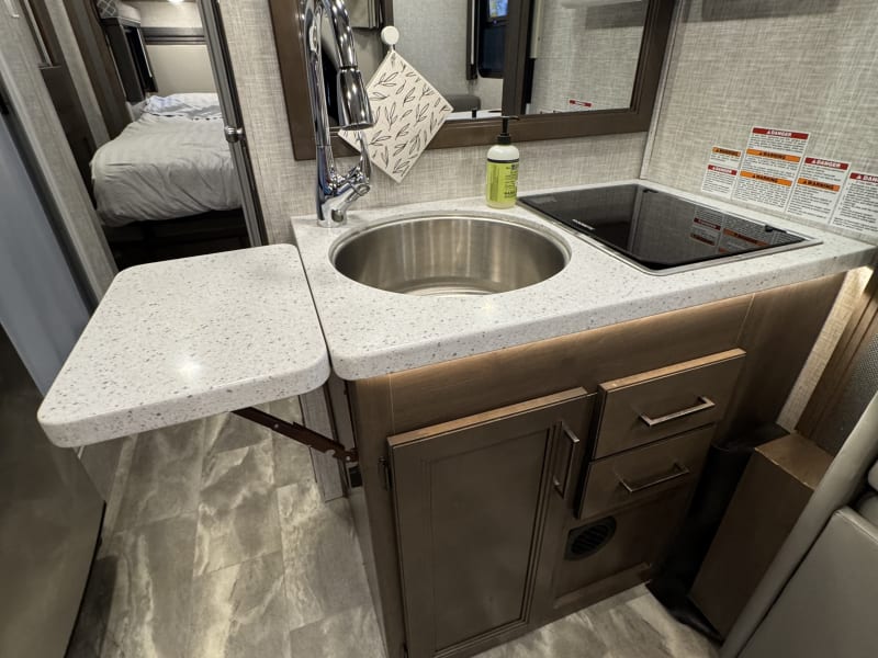 View of kitchen area with uncovered sink and counter top extension out. 