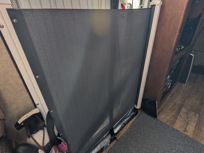 This is what it looks like when the magnetic door screen is closed and the dog barrier is rolled out from the right and hooked onto the metal white lip on the left. Our dogs (50 lbs each, so not tiny) respect it and try to look out from below it. Works well, though can take a bit of getting used to attaching it correctly.

On the far right, you can see the standing heater with modest cool air fan. Just beyond that are the stairs to the bedroom.