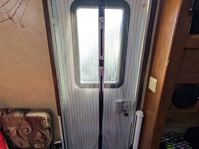 Magnetic door screen when closed. It seals well, though it is frail and can be a bit finicky.

On the left, under the bench seat, are stored all additional cooking appliances (photo below):
- toaster oven
- induction cooktop
- sandwich press/electric grill
- small rice cooker
- single cup coffee machine

To the right is the extendable dog barrier. Once the door screen is closed, it can be unrolled from the right and hooked on the the white lip on the left door jam (photo below).
