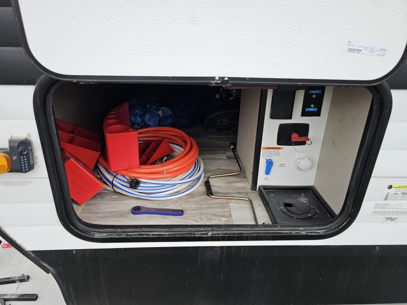 Service panel with hoses and tools needed during trip as well as panel to hook up water and cable. 