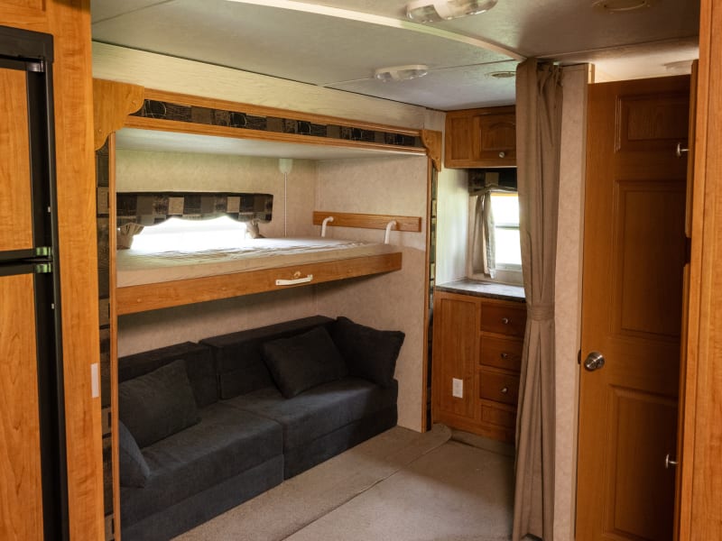 Sleeping area with bunk bed down. Max weight capacity for the bunk bed is 150 pounds. Each sofa section folds out into a full sized twin memory foam mattress. Side by side, they are the same size as a king bed. Curtain can be closed for privacy. 