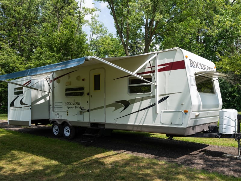 Driver side exterior with awning and slides out. 
