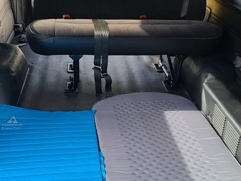 Sleep mats for two, looking from passenger seat back toward cargo area. 