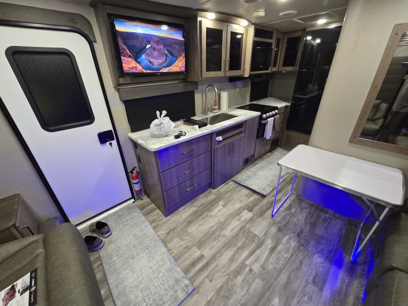 View of kitchen sink/faucet, stove and oven, and refrigerator, Roku smart TV, and folding table