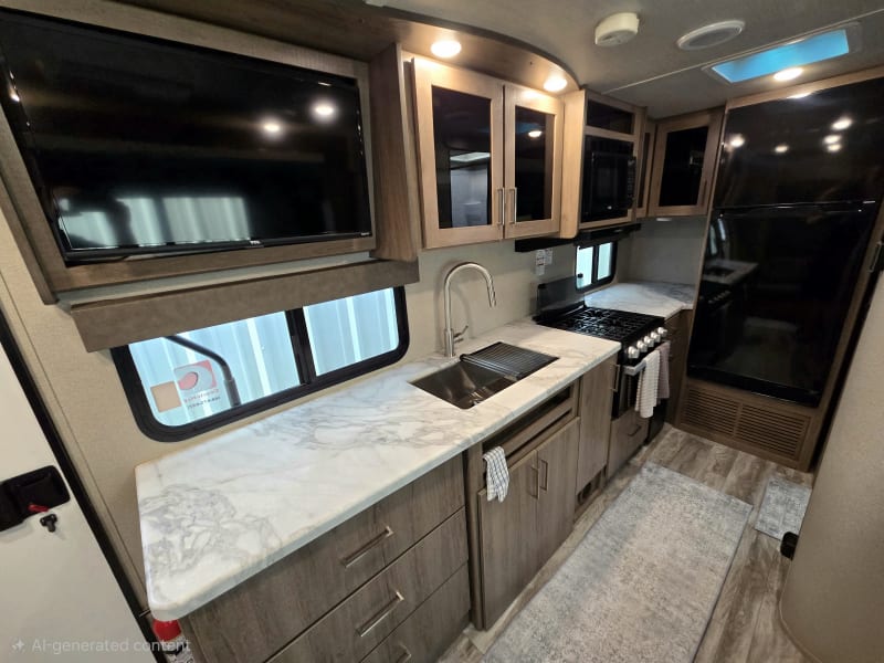 View of kitchen sink/faucet, stove and oven, and refrigerator, and Roku smart TV
