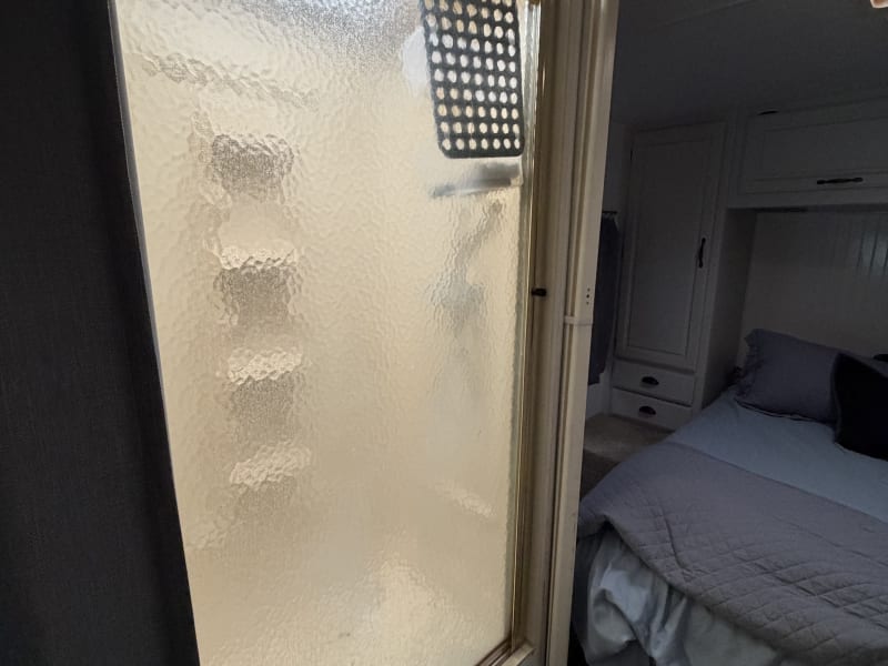 Shower door is frosted front no curtain but slider door closes on room side and curtain on the other for privacy in restroom hallway area