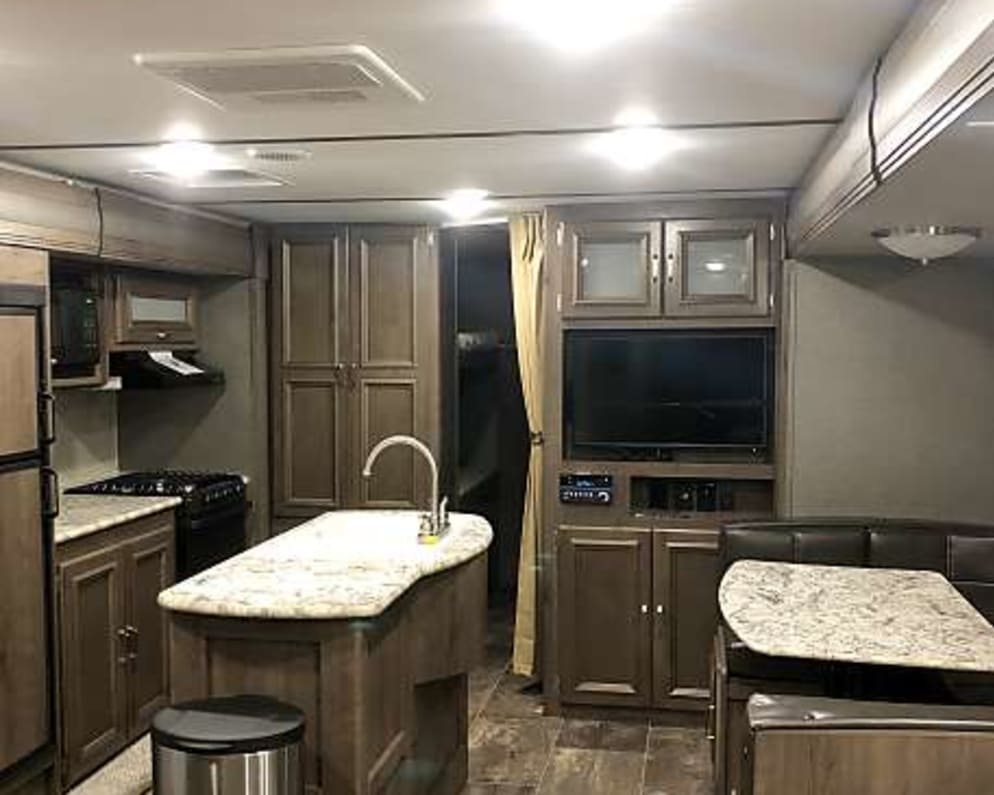 Main living area including kitchen island with double sink and u shaped spacious dinette. 