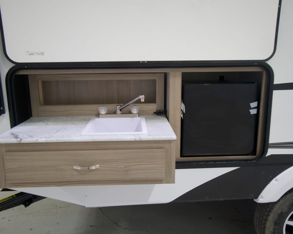 Outdoor kitchen with working sink and mini fridge. Perfect to save in and out of the trailer while barbecuing. 