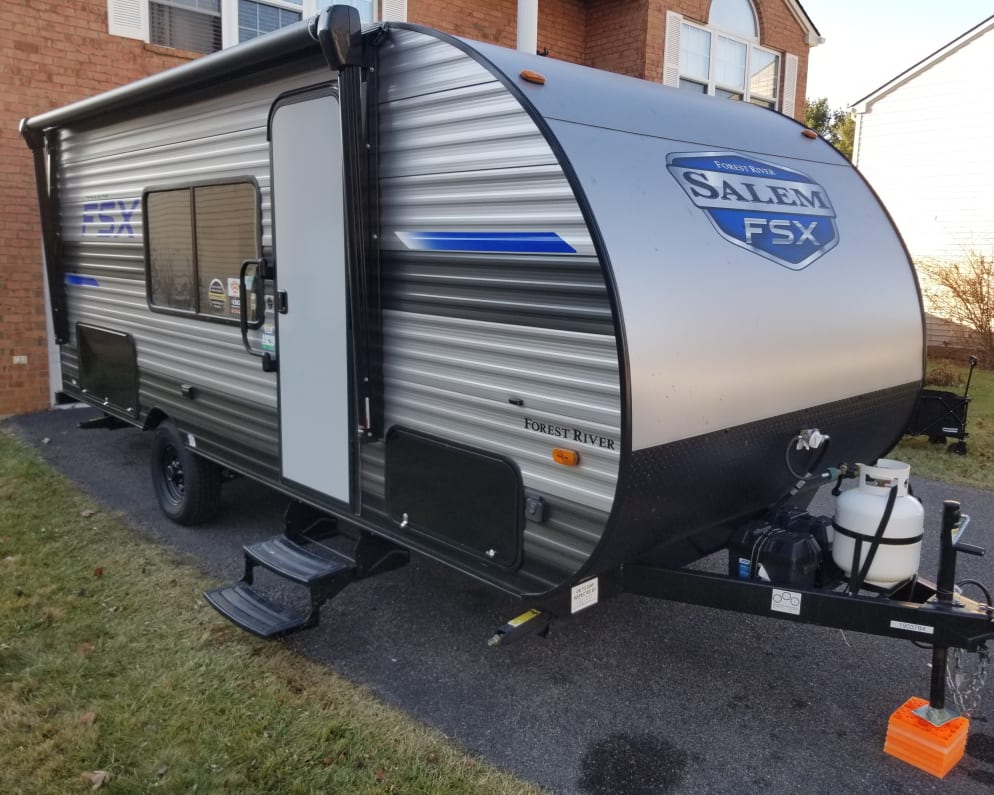 Flush passenger side view of the camper, tow approved. Offers large dinette window, retractable stairs, two under cabin storages and propane tank.