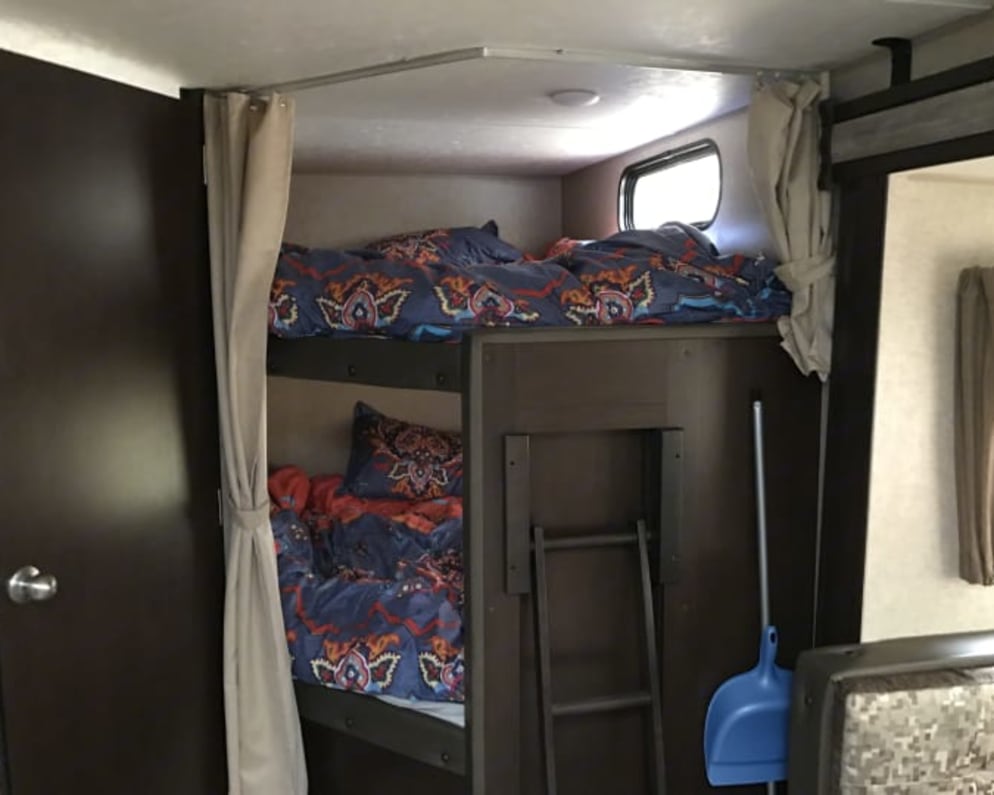 Bunk beds next to bathroom and dining room.