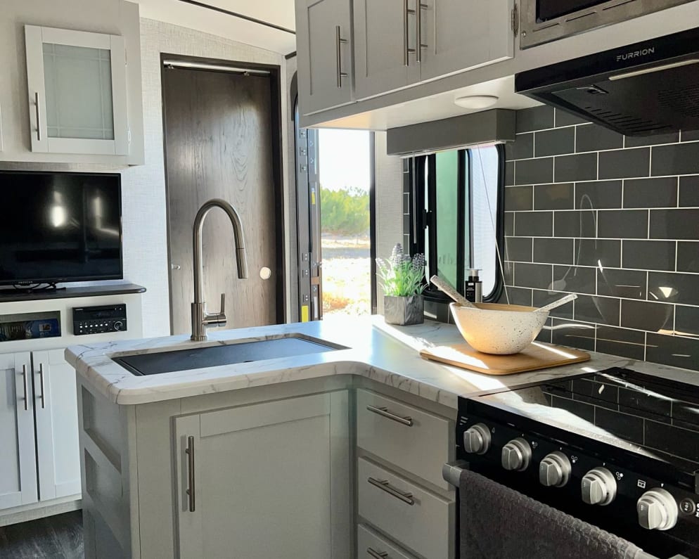 Spacious kitchen area with pots, pans, trash can and cleaning supplies under the sink