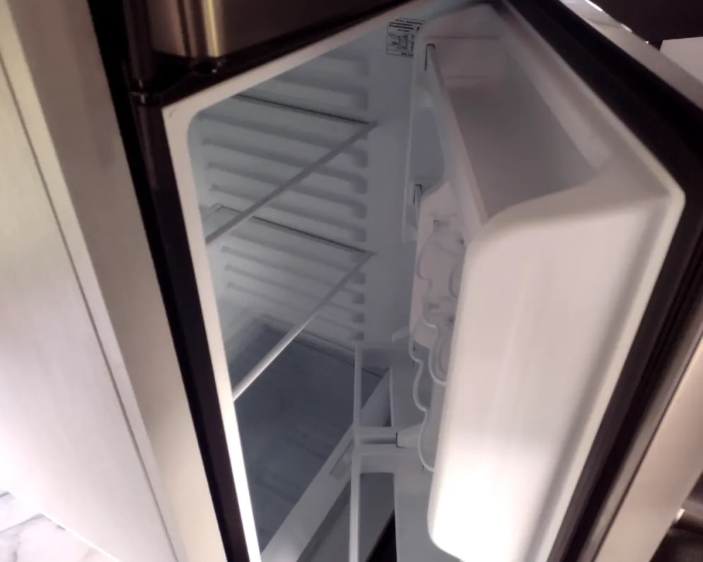 Open, empty, and clean refrigerator in an RV rental, ready for your travel essentials.