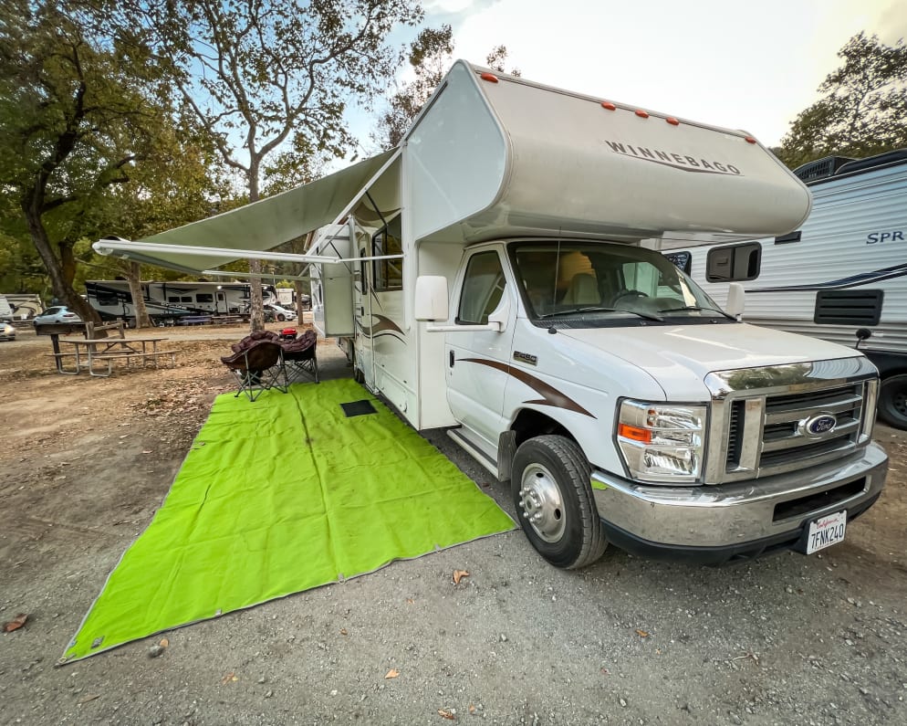 Equipped with awning, outdoor mat, 4 camping chairs, firepit, and BBQ grill.