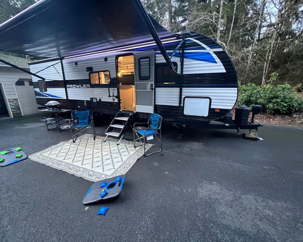 Outdoor set up. Awning, outdoor lights, outdoor speakers/Bluetooth sound system, chairs, corn hole, bbq with folding table, and outdoor rug