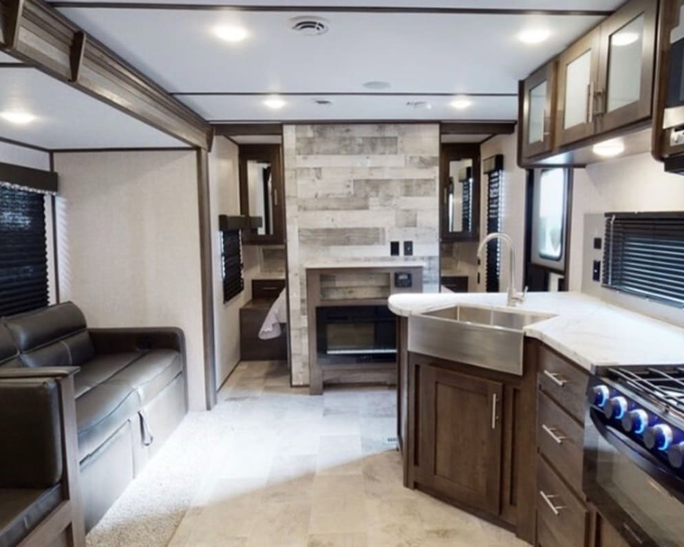 Living room with fireplace, pullout sofa, and farmhouse sink in kitchen