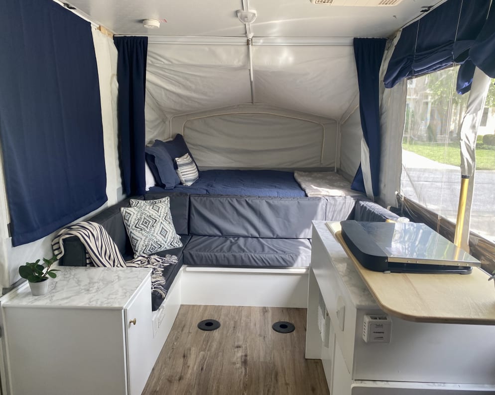 title='Email now about this 2013 Jayco Jay Popup Trailer RV for Rent in Kansas City, Kansas rental unit!' Cozy RV rental pop-up camper interior with convertible sofa, bed, and compact kitchen