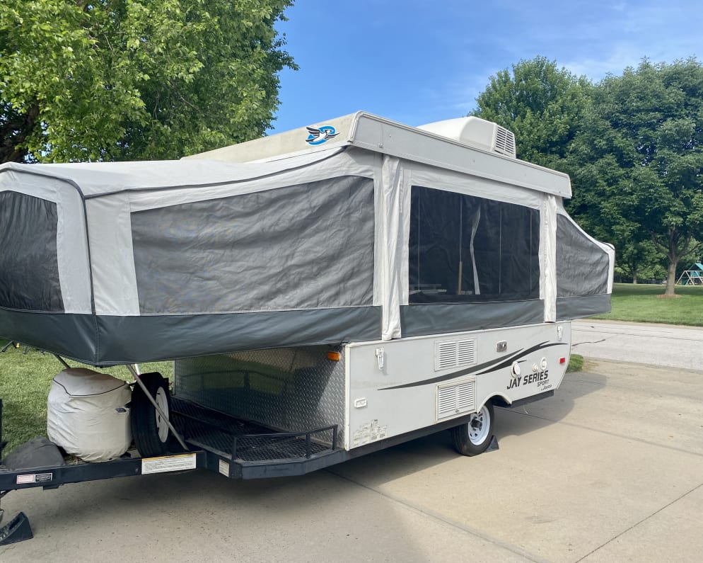 Grey pop-up RV rental (Jayco Jay Series) with AC, set up on a driveway for outdoor adventures.