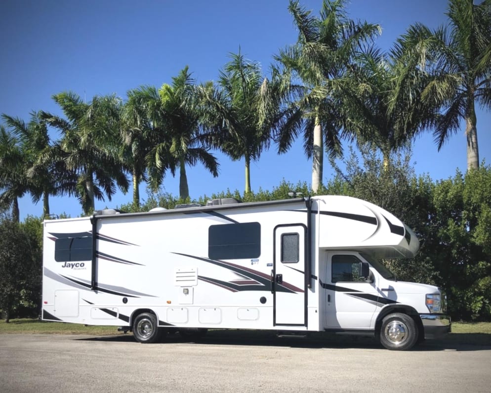 Embark on a tropical journey of serenity and freedom with our 2022 Jayco Redhawk 31F, beautifully captured against a backdrop of swaying palm trees. The photo exudes a sense of wanderlust, inviting you to escape the ordinary and embrace the allure of paradise. Imagine waking up to the gentle rustling of palm fronds, stepping outside to the warm embrace of the sun, and knowing that every day brings new adventures beneath the shade of these majestic trees. 