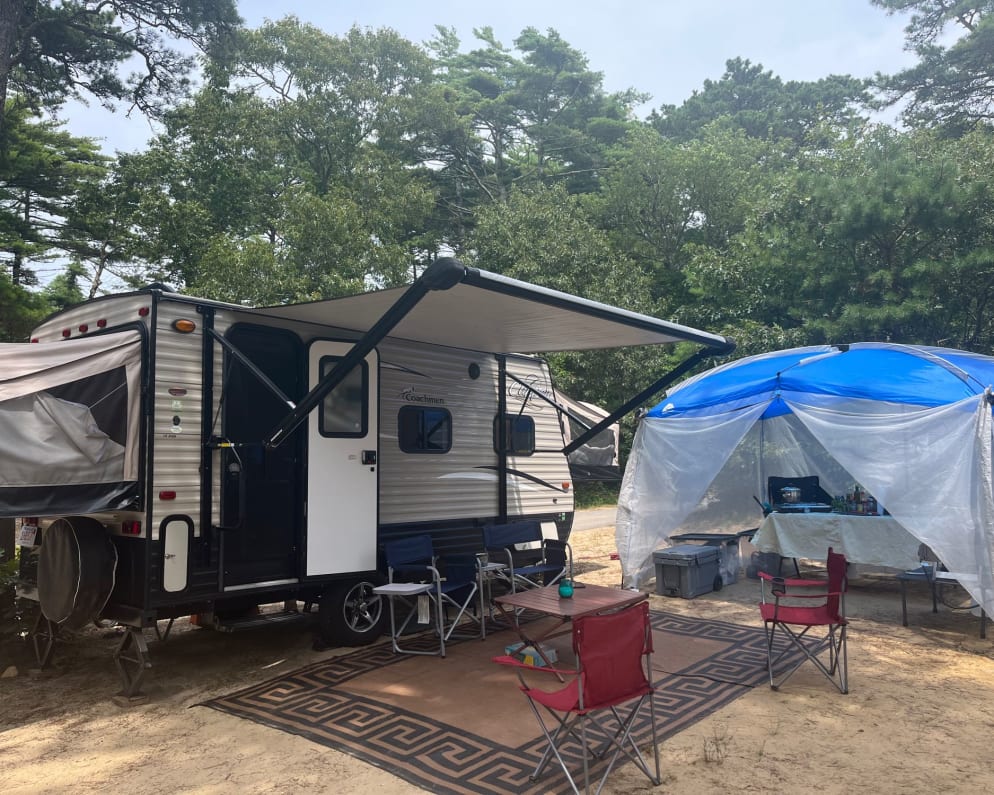 Camp setup with included chairs, outdoor rug and table.  Screen house and kitchen are add-ons. 