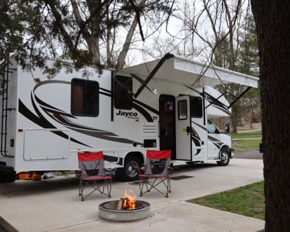 title='Click for more information about this 2021 Jayco Redhawk SE Class C RV for Rent in Fort Wayne, Indiana for rent!' White RV rental with extended awning, chairs