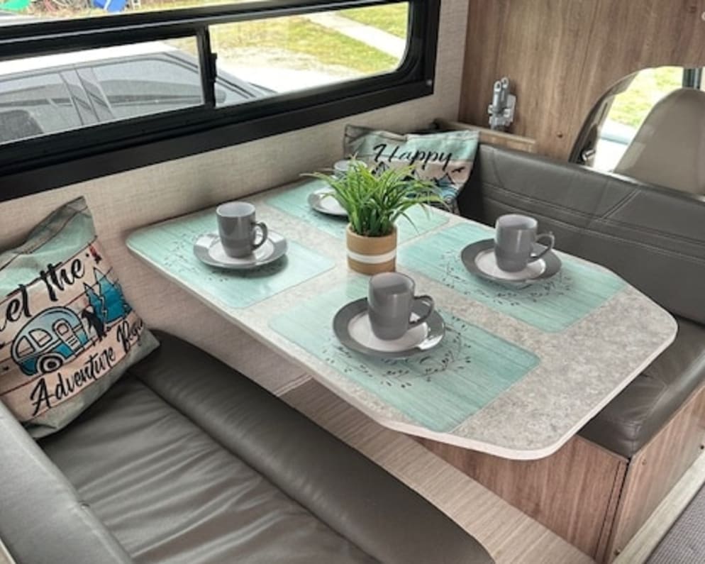 Cozy RV rental dinette interior: a compact table set for four with benches, perfect for meals on your road trip.