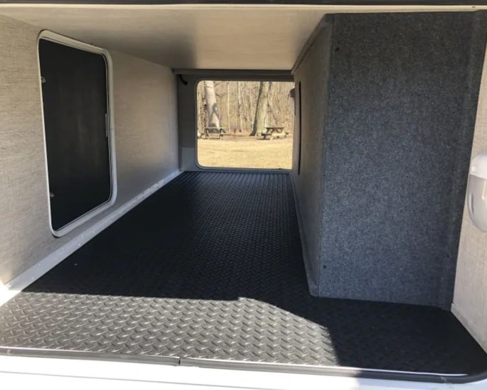 Spacious pass-through storage bay in an RV rental, featuring a durable black rubber floor and accessible from both sides.