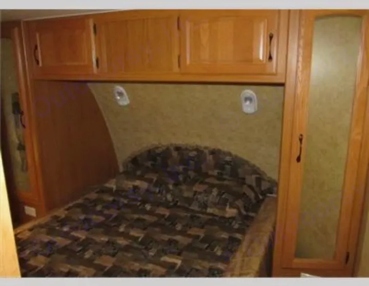 Cozy RV rental bedroom with a comfy bed, overhead cabinets, and built-in storage. Ideal for road trips and camping.. Keystone Laredo 2012