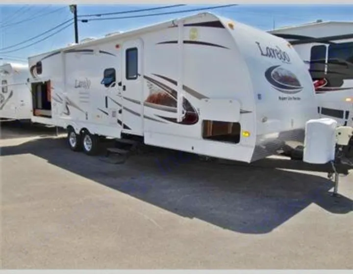 White Laredo travel trailer for rv rental, parked on asphalt.. Keystone Laredo 2012