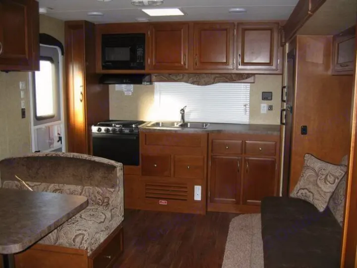 RV rental interior showcasing a well-equipped kitchen with stove, microwave, sink, and a comfortable dinette.. Eclipse Milan 2011