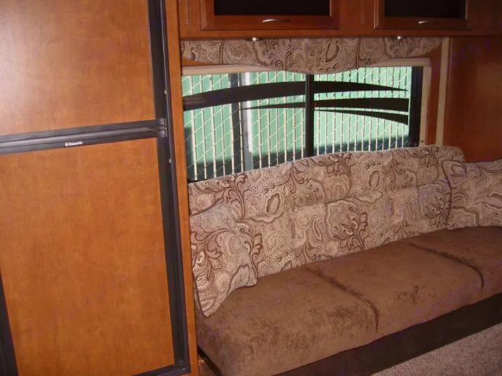 RV rental interior: Cozy living space featuring a patterned sofa, window, and Dometic refrigerator.. Eclipse Milan 2011