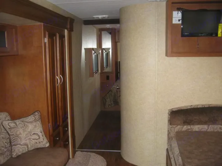 Step inside this cozy RV rental! Features include a comfortable living area, wood cabinetry, a mounted TV, and a hallway to the bedroom.. Eclipse Milan 2011