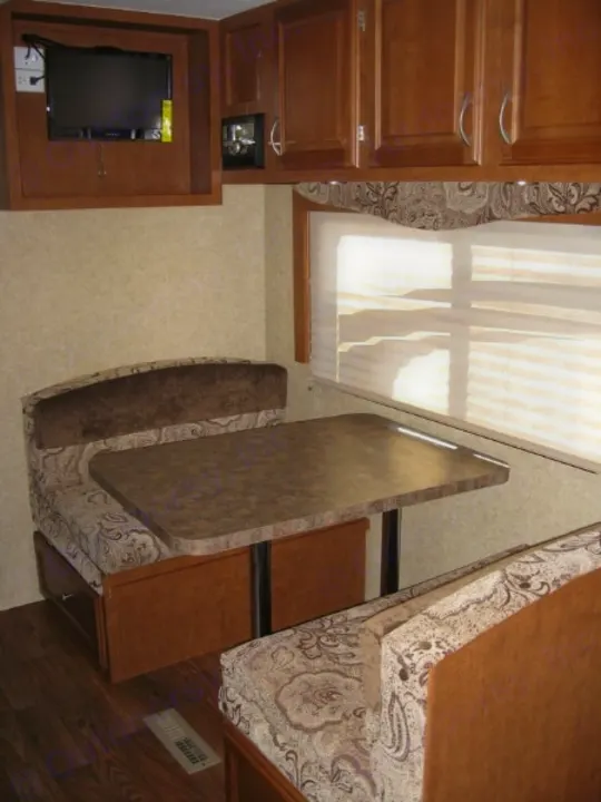 Cozy RV rental interior with a dinette, overhead cabinets, and a wall-mounted TV, perfect for travel comfort.. Eclipse Milan 2011