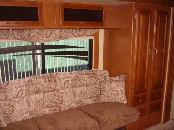 This RV rental interior features a cozy, patterned sofa, ample wooden cabinets, and a convenient wardrobe for your travels.. Eclipse Milan 2011