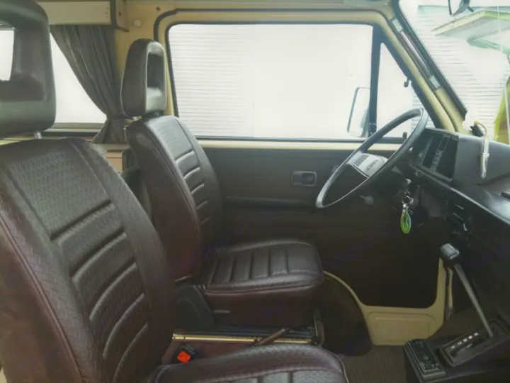 Spacious interior of a classic camper van, featuring brown textured seats and dashboard. Great for an rv rental journey.. Volkswagen westfalia 1984