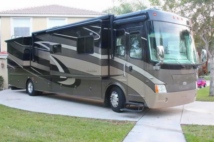 A luxury Mandalay motorhome in dark gray and tan, ideal for an RV rental. Slide-outs are extended, parked on concrete.. Thor Mandalay 2006
