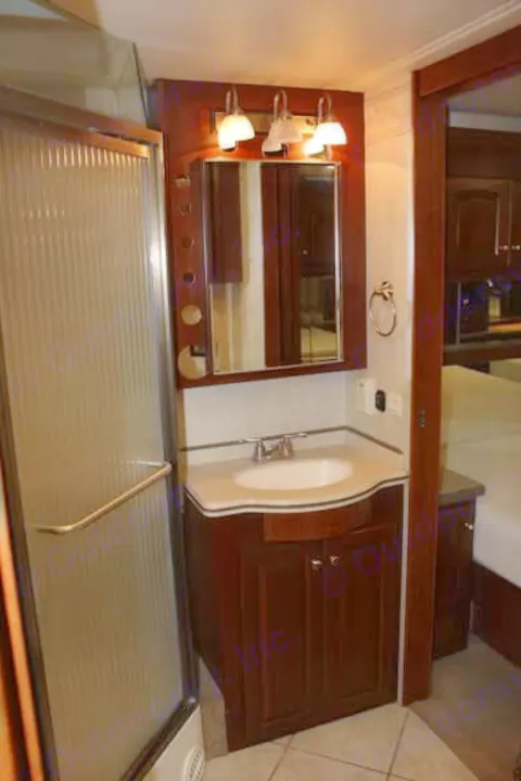 RV rental bathroom with spacious shower, wooden vanity, sink, and lighted mirror for comfort.. Thor Mandalay 2006
