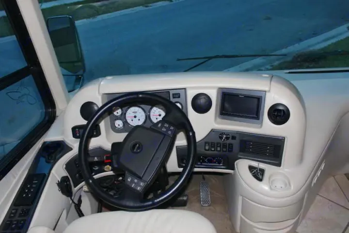 RV rental driver's area: Clean beige dashboard, steering wheel, gauges, and media screen ready for your journey.. Thor Mandalay 2006
