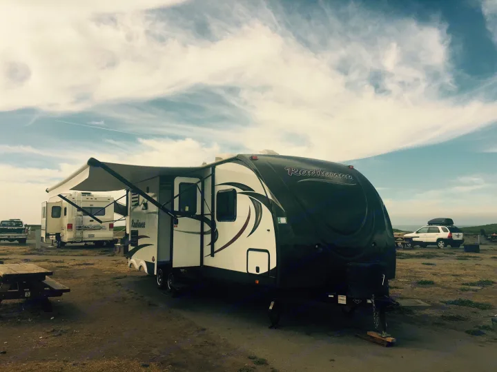 Spacious RV rental set up at a scenic coastal campsite under a cloudy sky, ready for a relaxing getaway.. Radiance 28BHIK 2016