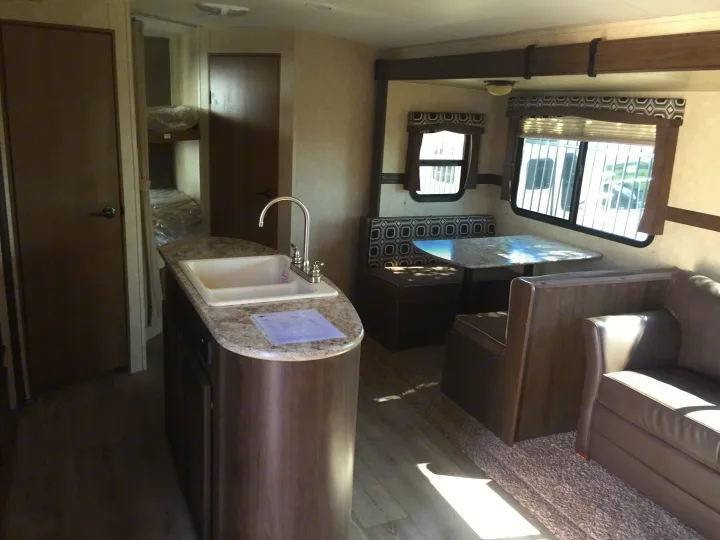 Spacious RV rental interior with kitchen island, dinette, sofa, and bunk beds. Ideal for family adventures.. Radiance 28BHIK 2016
