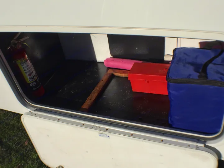 RV rental storage compartment with a red fire extinguisher, red toolbox, pink float, and blue bag. Ready for travel!. Forest River Sunseeker 2012