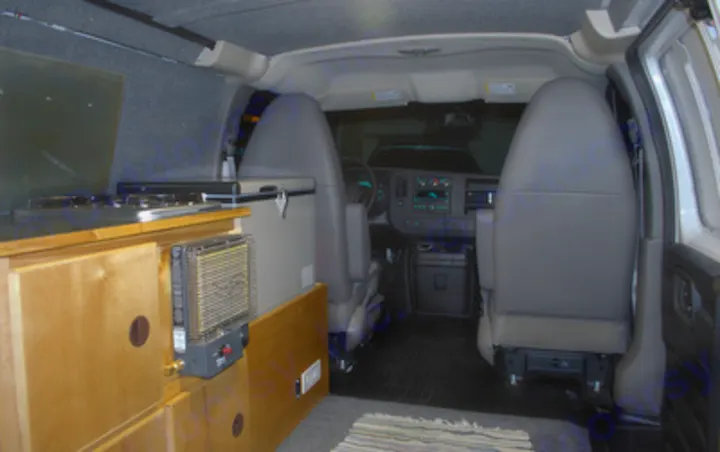 Inside a campervan: custom kitchen with stove, portable heater, fridge, and front seats. Perfect for rv rental!. Chevrolet Express G1500 AWD 2014