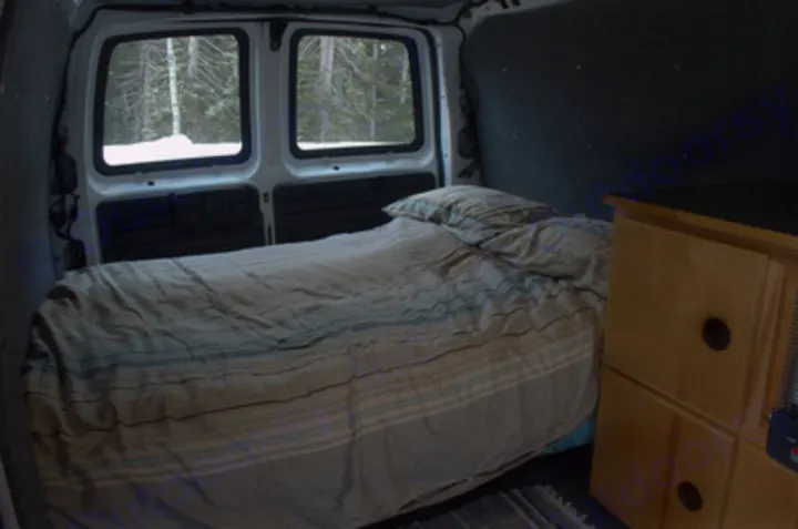 Cozy RV rental campervan interior: a comfy bed with snowy views, perfect for a road trip or camping.. Chevrolet Express G1500 AWD 2014