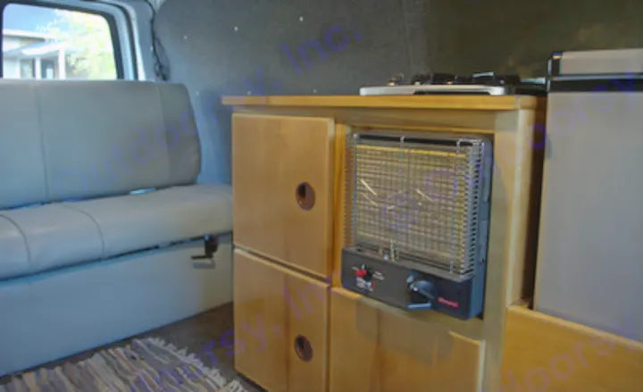 RV rental interior: custom wood cabinetry with an integrated heater, stove, and fridge, plus a comfy grey bench seat.. Chevrolet Express G1500 AWD 2014