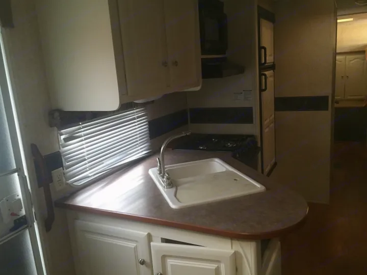 This RV rental features a well-equipped kitchen with a sink, countertop, cabinets, and stove.. Keystone Outback 2007