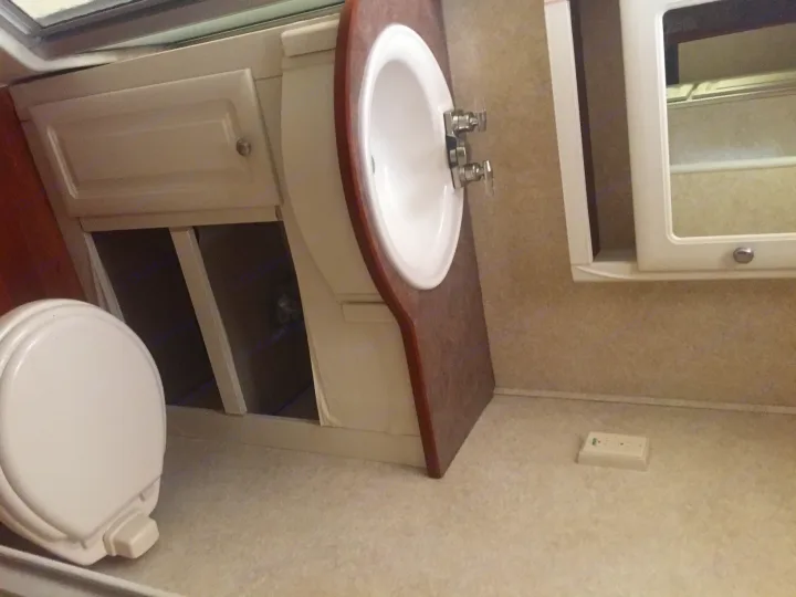 RV rental bathroom features a sink, vanity, mirrored cabinet, toilet, and open storage for compact living.. Keystone Outback 2007