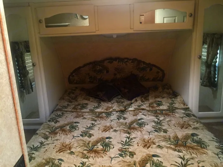 RV rental: Bedroom interior featuring a bed with floral comforter, upholstered headboard, and mirrored cabinets.. Keystone Outback 2007