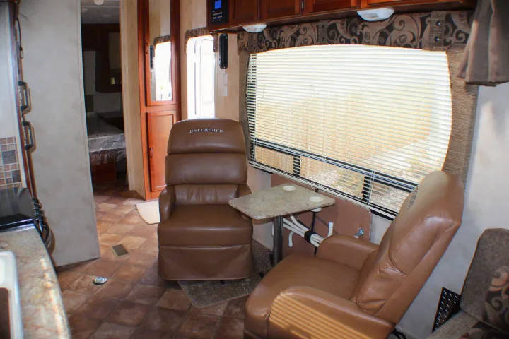 Spacious RV rental interior: brown recliners, table, and window. View to bedroom beyond.. Palomino Puma Unleashed 2013