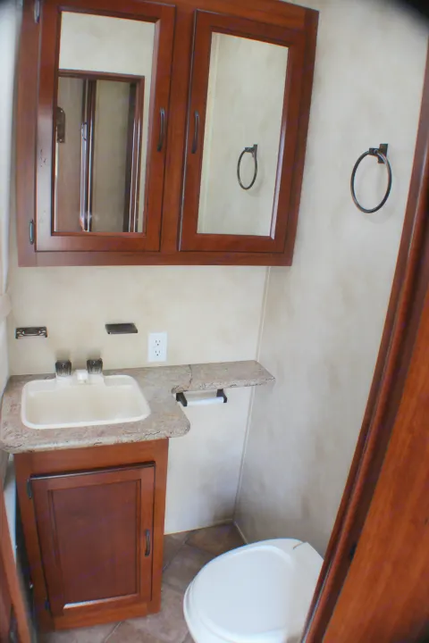 Compact RV rental bathroom with sink, mirrored medicine cabinet, and toilet. Essential amenities for travel comfort.. Palomino Puma Unleashed 2013