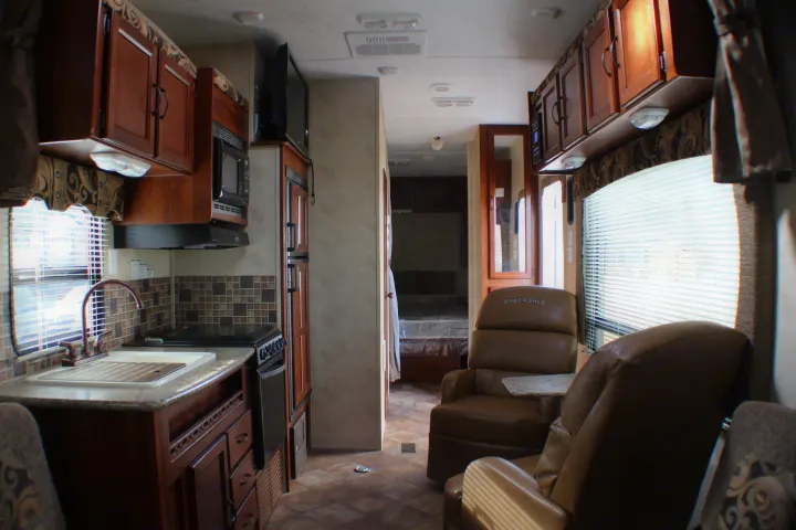 Spacious RV rental interior featuring a modern kitchen, comfortable living area, and a glimpse of the bedroom beyond.. Palomino Puma Unleashed 2013