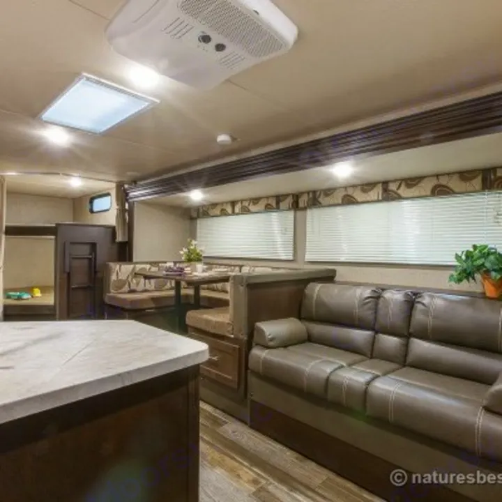 This RV rental interior offers a comfortable living space with a brown sofa, dinette, and bunk beds. Ideal for your next adventure.. Forest River Cherokee 2017